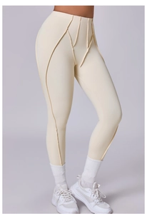 Dettaglio dei pantaloni da yoga beige a vita alta con cuciture curve decorative e tessuto opaco