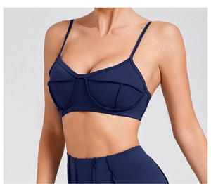 Detail view of navy blue sports bra with thin straps and decorative structural stitching