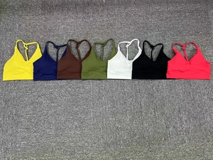 Flat lay detail of cross-back sports bras in seven vibrant colors on textured background