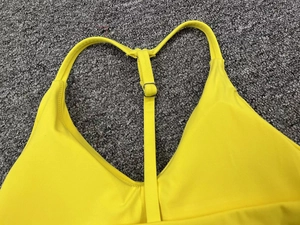 Detail view of yellow sports bra with adjustable straps and racerback design
