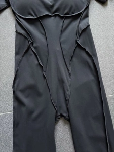 Détail d'une combinaison de sport noire avec coutures géométriques et texture en nylon mat