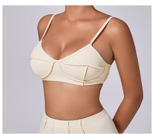 Detailed view of cream sports bra with thin straps and supportive curved seam stitching