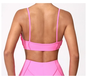 Macro shot of hot pink sports bra back with thin straps and seamless high-waist leggings