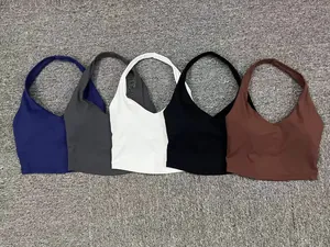 Cinq hauts de sport dos nu extensibles en couleurs variées posés à plat sur fond en peluche