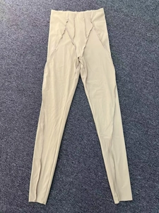Dettaglio dei pantaloni da yoga beige a vita alta con cuciture rinforzate su tappeto