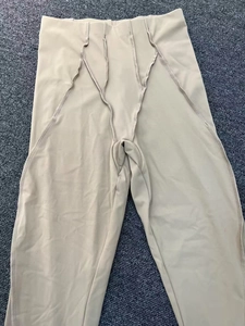 Dettaglio dei pantaloni da yoga a vita alta con cuciture modellanti color albicocca