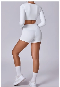 Rear view of white long-sleeve crop top and high-waist fitness shorts for women