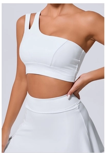 Détail du soutien-gorge de sport blanc à une épaule avec bride asymétrique et jupe de fitness
