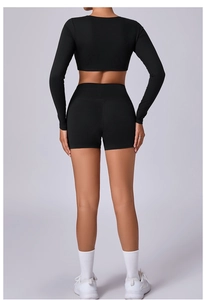 Back view of black long sleeve cropped fitness top and high waist compression shorts