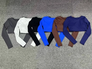 Detailed flat lay of six colorful long sleeve cropped yoga tops in diverse athletic shades