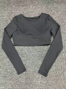 Detailed view of dark grey long sleeve crop top fitness shirt on a textured surface