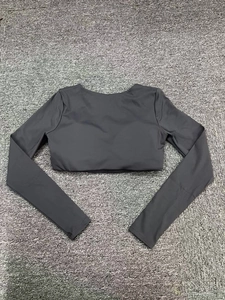 Flat lay of a grey cropped long sleeve gym top on a soft plush carpeted background