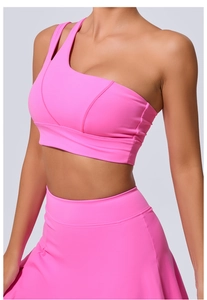 Détail d'un haut de sport rose asymétrique et jupe assortie en tissu athlétique lisse