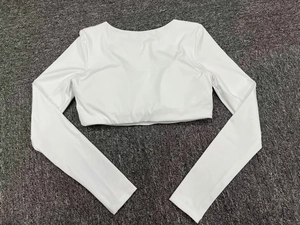 Close-up of a white cropped long-sleeve fitness top laid flat on a grey textured surface