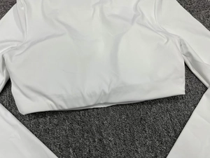Close-up detail of white long-sleeved yoga top with built-in chest pads and elastic fabric