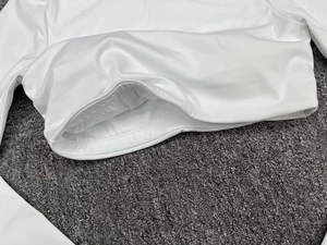 Close-up of white long sleeve fitness top showing professional double-stitch hem details