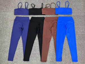 Flat lay of seamless yoga sets in navy, black, brown, and royal blue on textured background