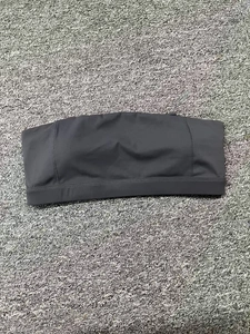 Soutien-gorge de sport bustier gris foncé extensible posé sur un tapis gris