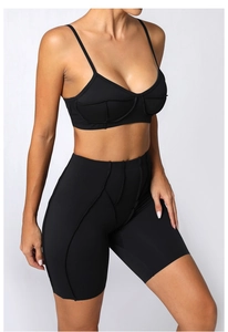 Détail d'un ensemble de sport noir avec short taille haute, brassière et coutures