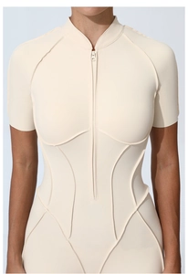Close-up of beige athletic bodysuit featuring a zipper front and slimming seam details