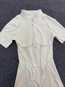 Detail of cream yoga bodysuit featuring a high collar with front zipper and contrast stitching