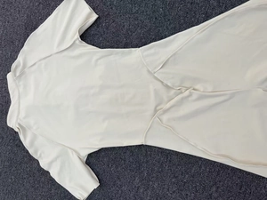 Flat lay detail of cream short sleeve yoga bodysuit with collar and stretch fabric