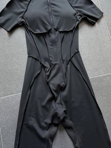 Close-up of black short sleeve yoga bodysuit with front zipper and ergonomic seam detailing