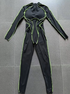 Détail d'un body noir à manches longues avec des surpiqûres vert fluo contrastées