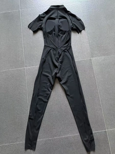 Detail of black sports bodysuit showing heart-shaped cutout back on yoga fabric
