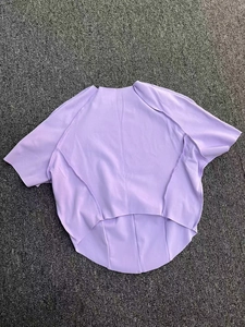 Détail du haut de yoga violet avec coutures uniques et ourlet incurvé asymétrique moderne