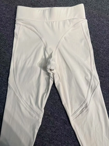 Détail du legging de yoga à taille haute avec coutures en V sur le tissu blanc crème