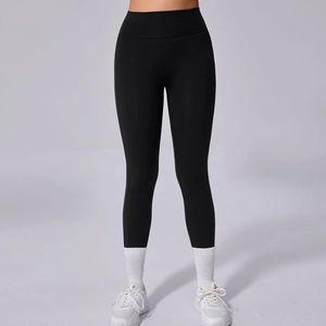 Detail van de zwarte yoga broek met hoge taille, compressiestof en witte sportschoenen