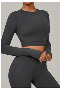 Détail du crop top de yoga gris anthracite avec passe-pouces et coutures courbes décoratives