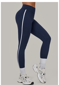 Seitenansicht der blauen High-Waist Yoga-Hose mit weißen Streifen und Turnschuhen