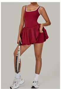 Detail of burgundy tennis dress featuring pleated hem, contrast trim and ball pocket