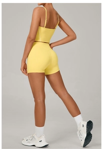Detail showing high-waisted yellow yoga shorts and criss-cross back sports bra