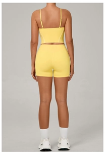 Detail view of bright yellow yoga set featuring open back tank top and high-waist sports shorts