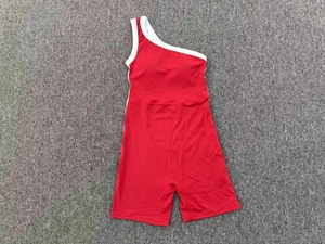 Body de yoga rouge à une épaule avec passepoil blanc posé à plat sur tapis gris