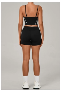 Rear view of black high-waisted sports shorts and cross-back crop top with white piping