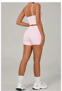 Detail of light pink yoga set featuring a strappy sports bra and high-waisted gym shorts