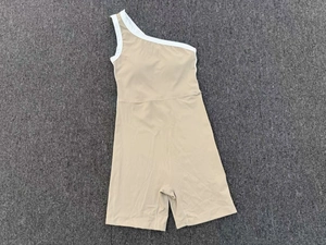 Détail à plat d'un body de yoga beige à une épaule avec bordure blanche contrastée