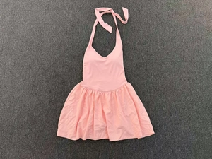 Detailed flat lay of pink halter neck tennis dress with pleated skirt on textured background