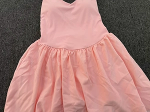 Flat lay detail of pink tennis dress with V-neckline and pleated flared skirt design