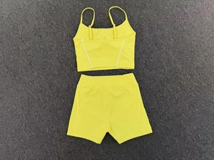 Flat lay of yellow yoga set with strappy crop top and seamless high waist shorts on grey rug
