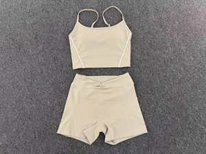 Flat lay of beige two-piece yoga set with cross-back sports bra and high-waist shorts