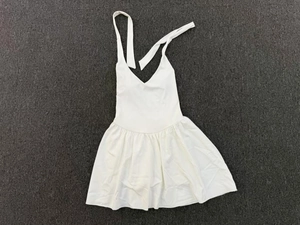 Detailed flat lay of white halter neck tennis dress with pleated skirt on gray surface