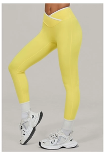 Detail of high waist yellow yoga leggings with crossover V-cut and white trim accents