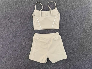 Flat lay of a beige yoga set with adjustable thin straps and white curved line detail