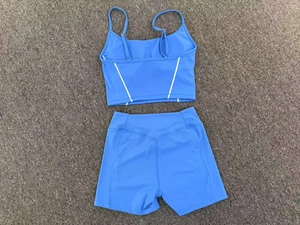 Flat lay of sky blue yoga set featuring a strappy tank top and high waisted biker shorts