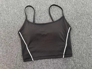 Detailed flat lay of black yoga sports bra with white side piping and adjustable straps